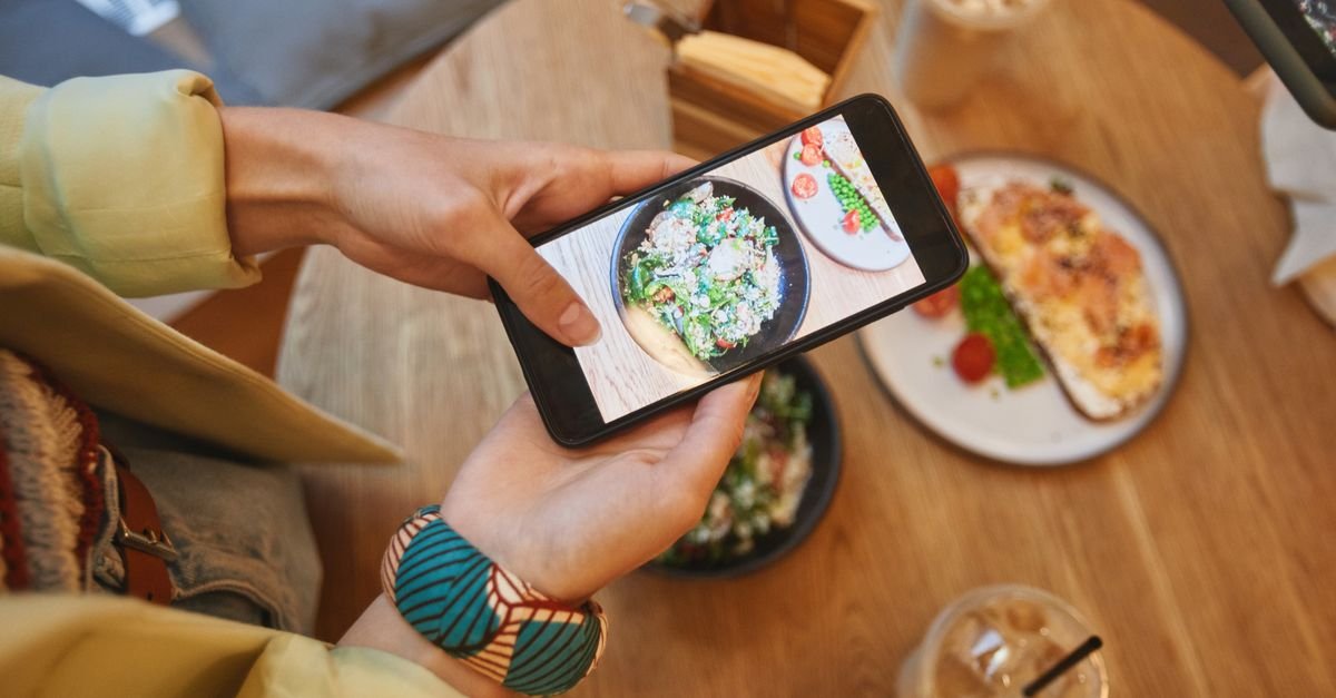 Person fotografiert Restaurantessen mit einem Smartphone